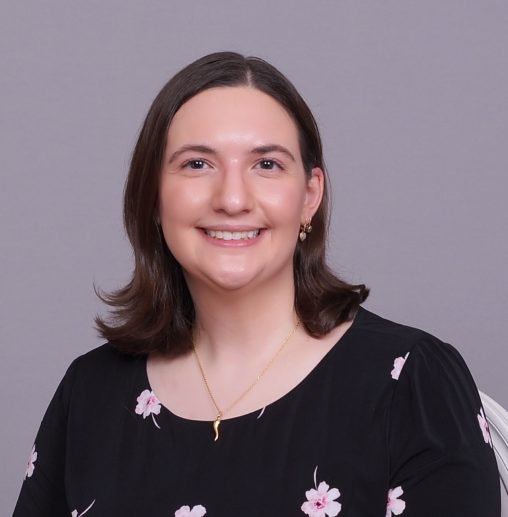 Dr. Quartuccia on a gray background. Her hair is down and she's wearing a black shirt with flowers.