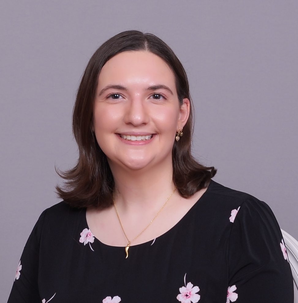 Dr. Quartuccia on a gray background. Her hair is down and she's wearing a black shirt with flowers.
