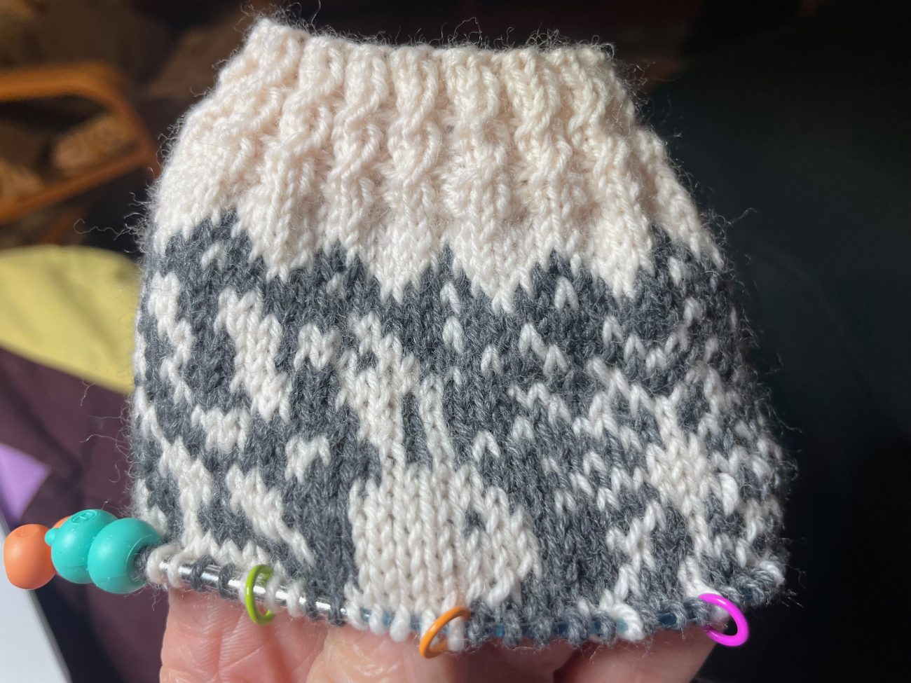 A partially knit sock in gray and cream with a rabbit design