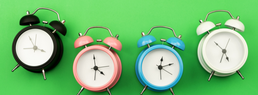 Four small clocks against a green background