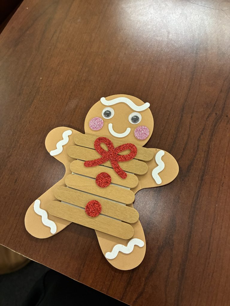 A gingerbread man made of foam atop a wooden table.
