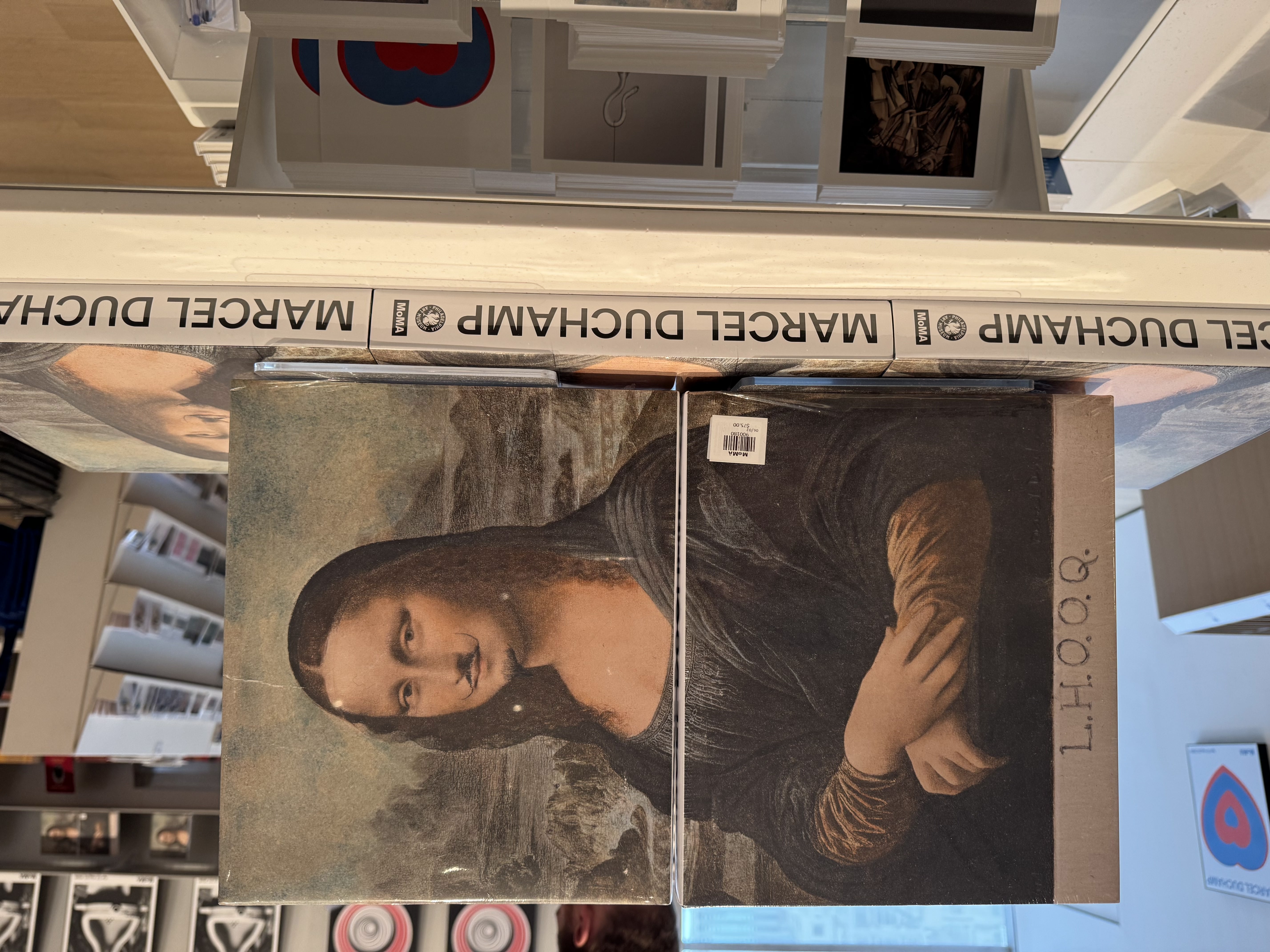 Shrink wrapped Duchamp exhibition catalogs in the MoMA gift shop, with the mustached Mona Lisa from L.H.O.O.Q