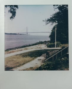 Woman is working in a garden in front of the Verrazano Bridge