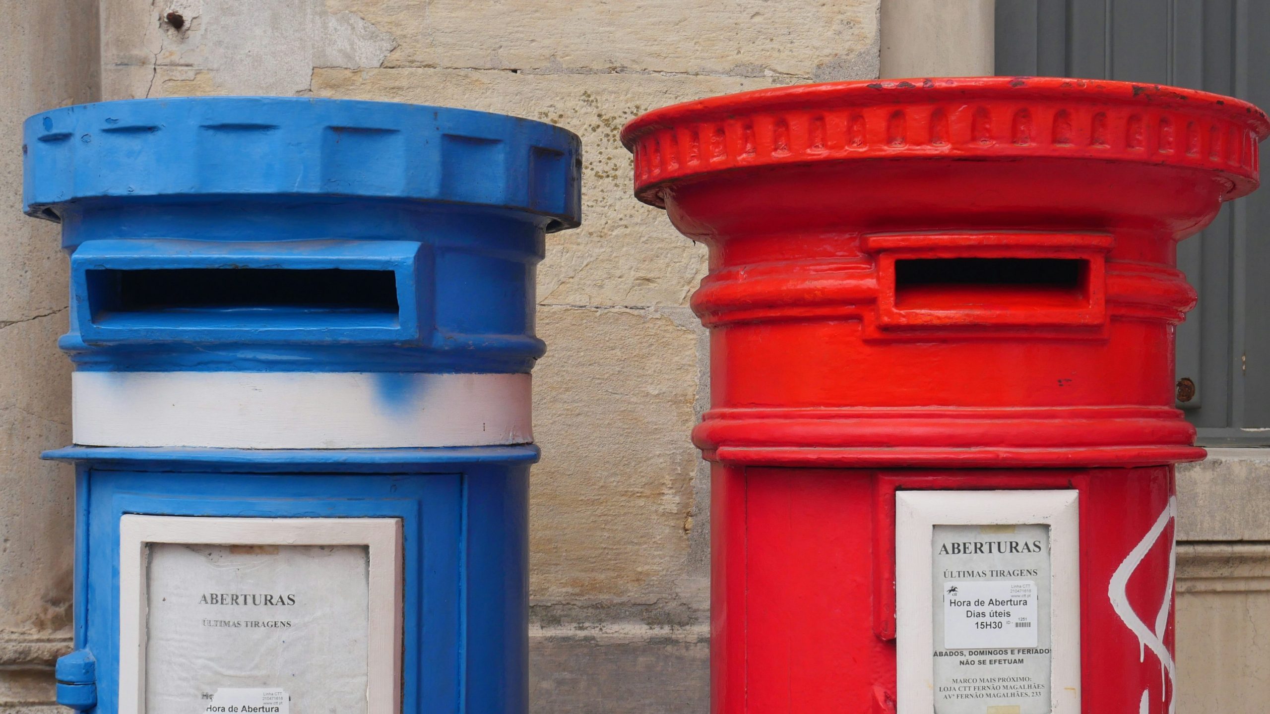 Two mail post boxes, one blue on the left, and one red on the right.