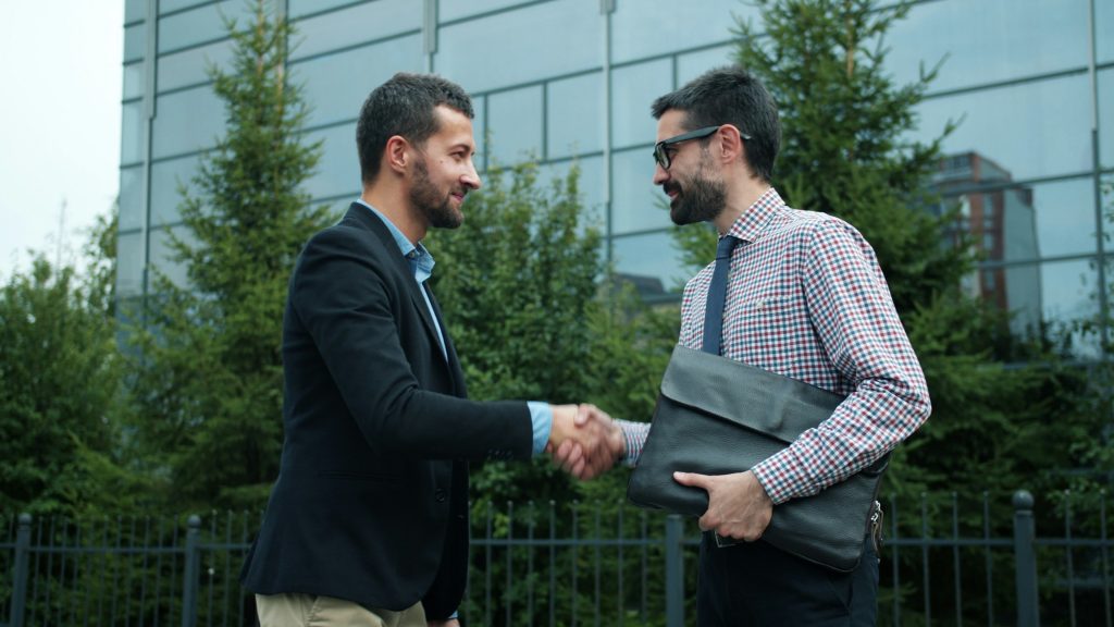 Two men shaking hands, one is holding a briefcase. Presumably they just closed a deal.