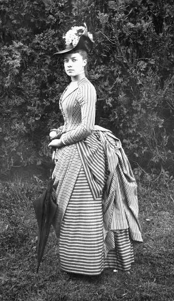 Woman in an elegant dress with a serious face posing for the camera.