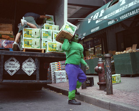 Man dressed as the Hulk lifting boxes of supplies from a truck.