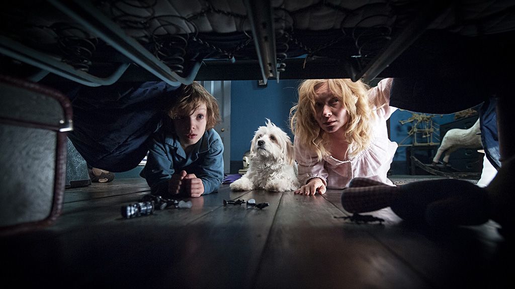 A scene from The Babadook where Amelia, her son Samuel, and their dog are looking under his bed for monsters.