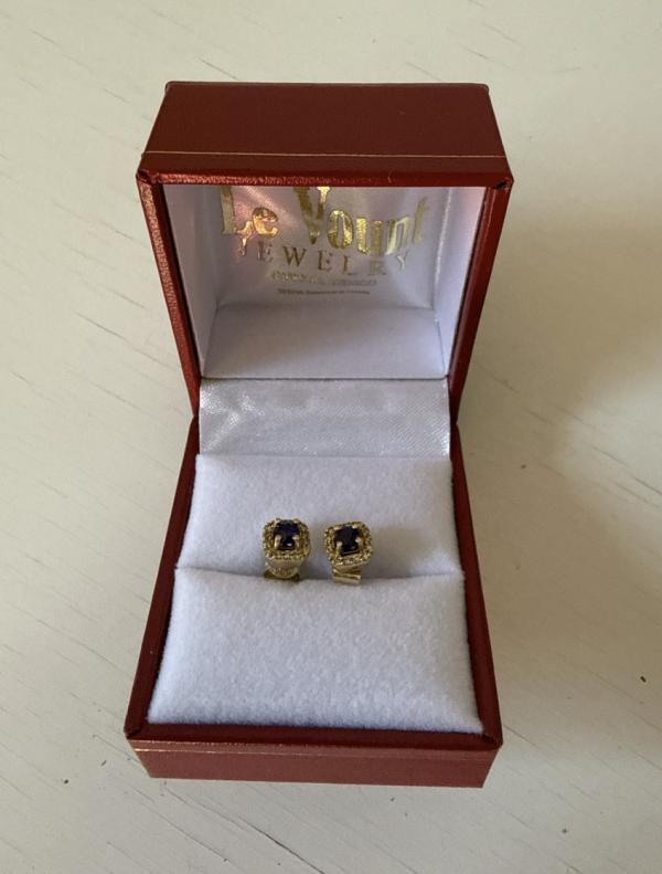 A picture of Canadian Gold Sapphire Earrings inside an opened red box placed on a table.